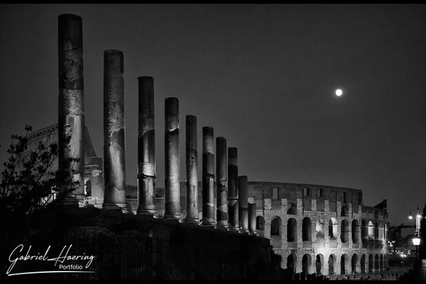 Black and white night view of the Colosseum and Roman columns