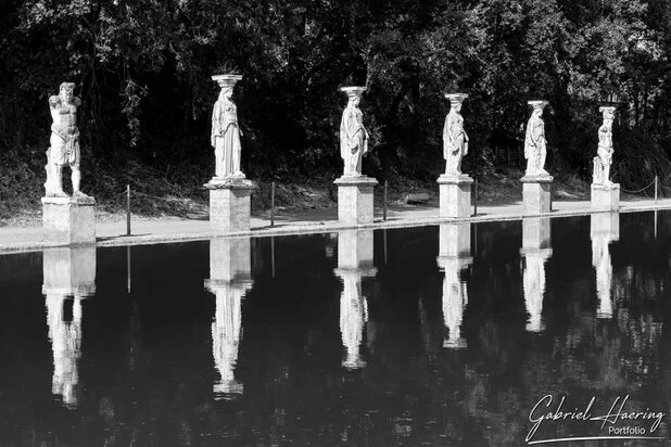 Black and white statues reflected in water at Villa Adriana near Rome